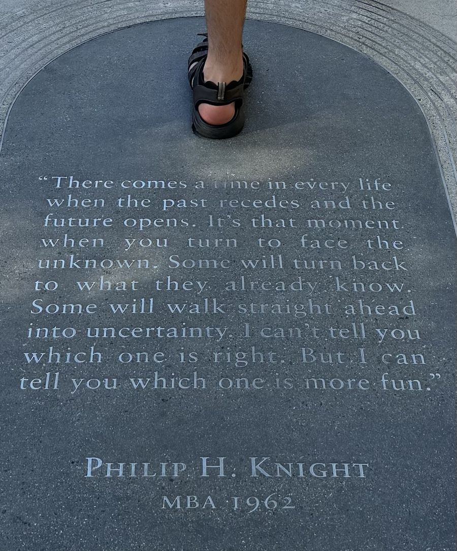 Engraved stone plaque in the ground with the Philip H. Knight quote, Henrique's sandal at the top edge